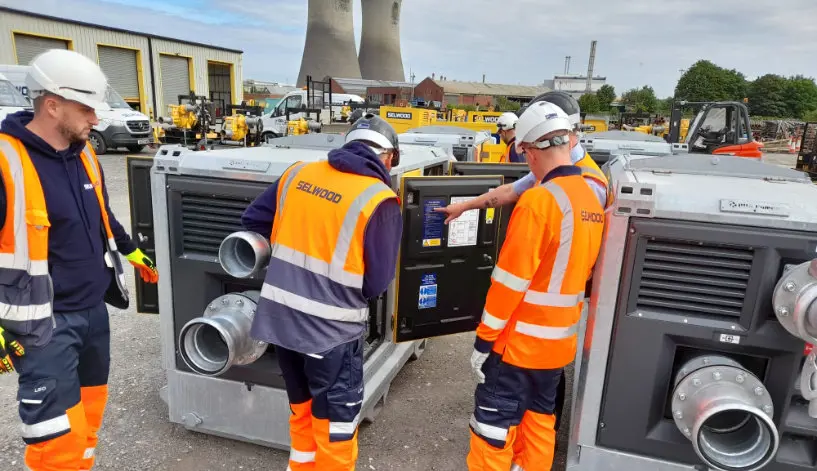 Selwood engineers reviewing a pump with a power station in the background